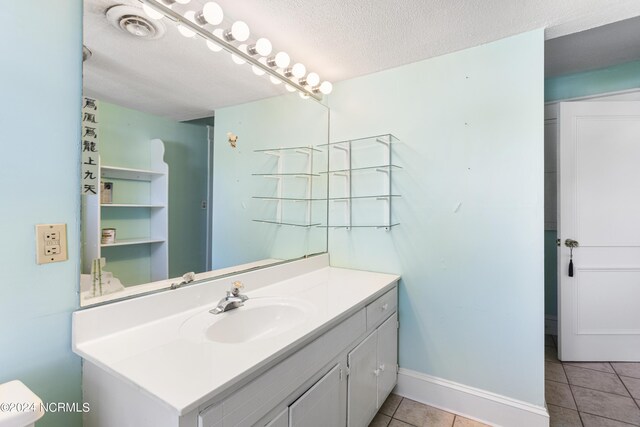 bathroom featuring a textured ceiling, tile patterned flooring, visible vents, vanity, and baseboards