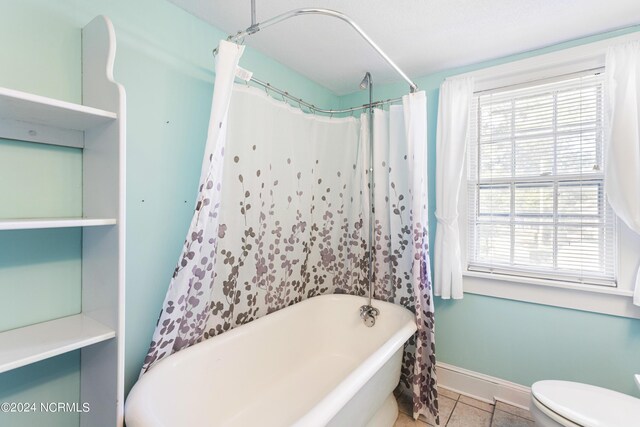 bathroom with plenty of natural light, toilet, shower / tub combo with curtain, and tile patterned floors