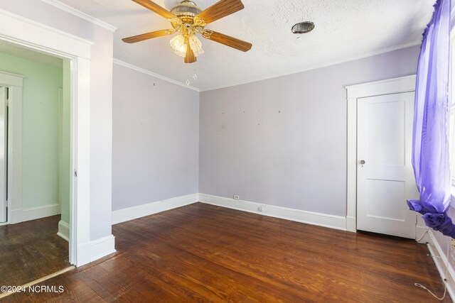 empty room featuring ceiling fan, a textured ceiling, dark wood-type flooring, and ornamental molding