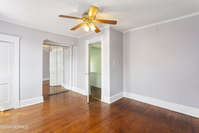 unfurnished bedroom with baseboards, a textured ceiling, wood finished floors, and crown molding