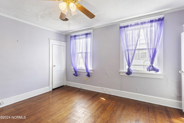 spare room with a textured ceiling, ornamental molding, wood finished floors, and baseboards