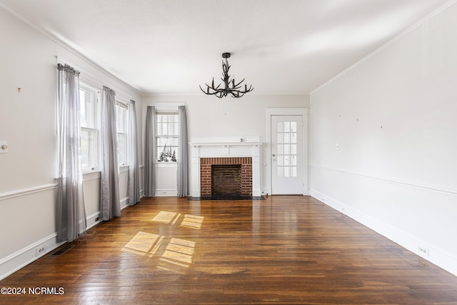 unfurnished living room with baseboards, ornamental molding, wood finished floors, a fireplace, and a chandelier