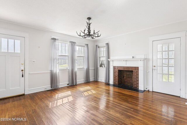 unfurnished living room featuring hardwood / wood-style flooring, a fireplace, crown molding, and a healthy amount of sunlight