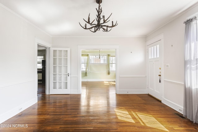 foyer entrance with a notable chandelier, wood finished floors, visible vents, baseboards, and crown molding