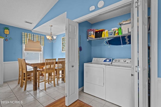 washroom with light tile patterned floors, a chandelier, washer and clothes dryer, and a textured ceiling