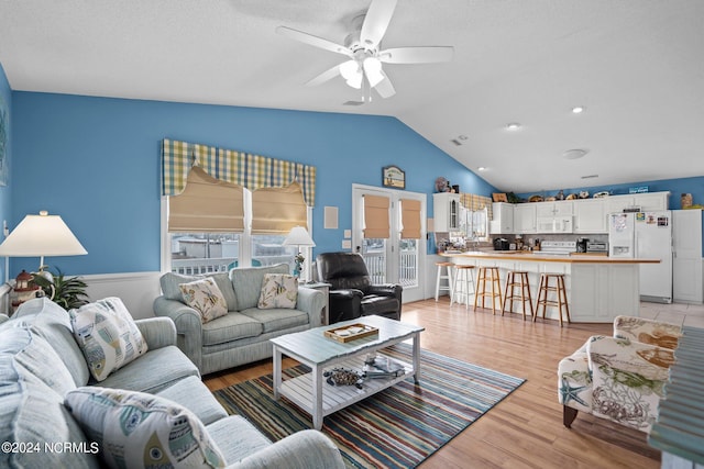 living room with lofted ceiling, a wealth of natural light, ceiling fan, and light hardwood / wood-style floors