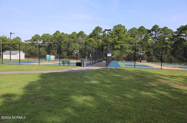 view of home's community featuring fence, community basketball court, and a lawn