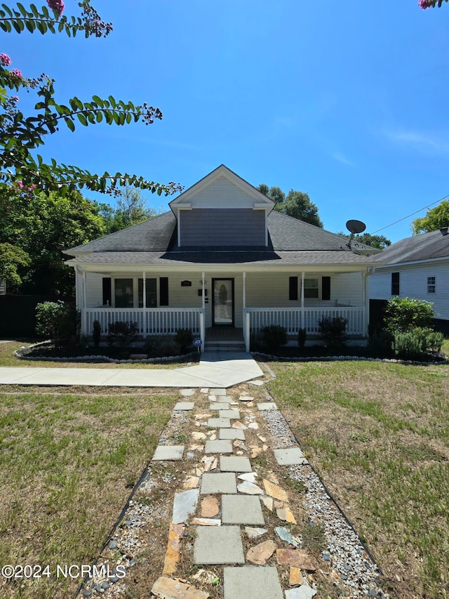 farmhouse inspired home featuring a porch and a front lawn