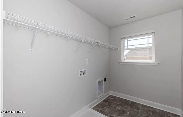 laundry area featuring electric dryer hookup, hookup for a washing machine, and dark tile patterned flooring