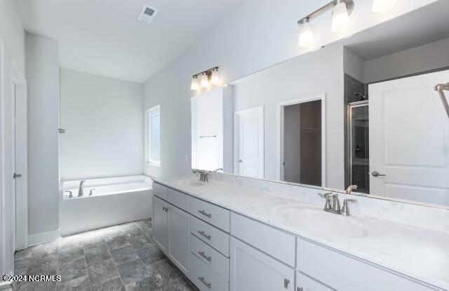 bathroom with dual vanity, tile patterned floors, and a tub to relax in