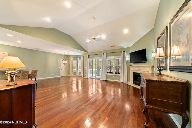 living room featuring a tile fireplace, lofted ceiling, dark hardwood / wood-style floors, and ceiling fan