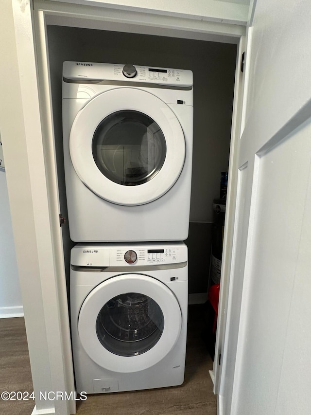 washroom featuring stacked washer / dryer, laundry area, baseboards, and wood finished floors