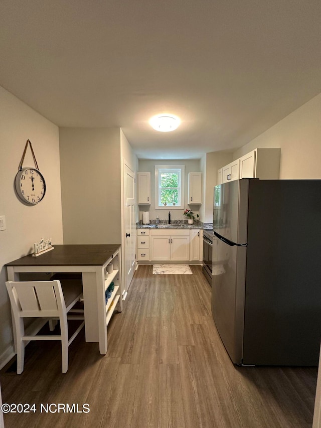 kitchen with white cabinets, sink, appliances with stainless steel finishes, and hardwood / wood-style floors