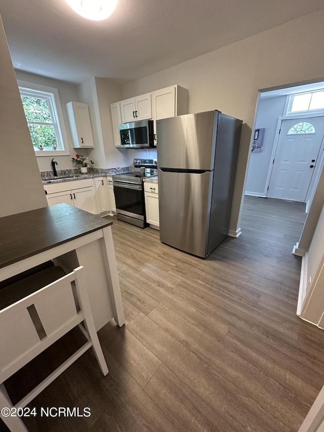 kitchen with dark wood-style flooring, a sink, baseboards, white cabinets, and appliances with stainless steel finishes