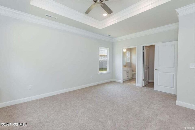 unfurnished bedroom featuring connected bathroom, crown molding, ceiling fan, a raised ceiling, and light colored carpet