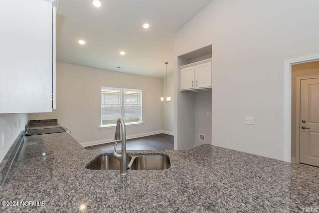 kitchen with white cabinetry, pendant lighting, sink, and dark stone countertops