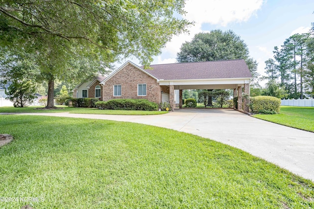 ranch-style home featuring brick siding, concrete driveway, fence, a carport, and a front yard