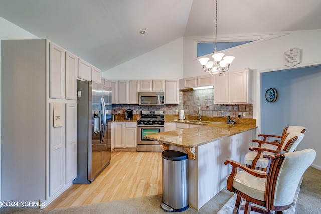 kitchen featuring a kitchen breakfast bar, appliances with stainless steel finishes, light hardwood / wood-style floors, decorative backsplash, and kitchen peninsula