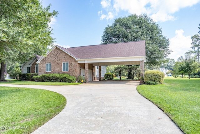 view of front facade with a front yard, brick siding, driveway, and roof with shingles