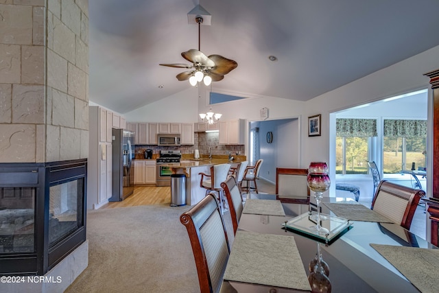 dining space featuring high vaulted ceiling, ceiling fan with notable chandelier, and light colored carpet