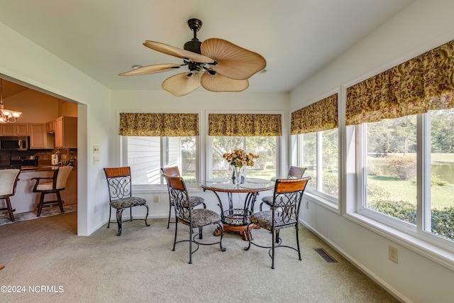 sunroom with a wealth of natural light, visible vents, and ceiling fan with notable chandelier