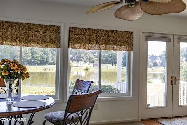 sunroom featuring ceiling fan, a water view, and french doors