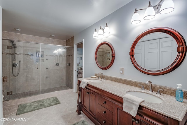 bathroom with double sink vanity, a shower with shower door, and tile patterned flooring