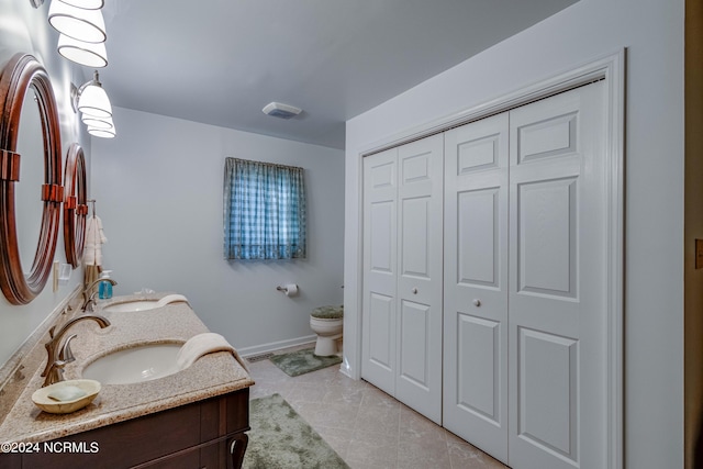 bathroom with double sink vanity, tile patterned flooring, and toilet