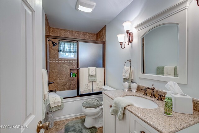 bathroom with tile patterned flooring, shower / bath combination with glass door, vanity, and toilet