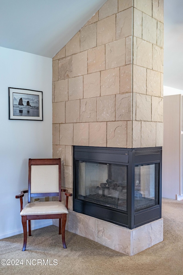 sitting room with a multi sided fireplace, carpet flooring, and lofted ceiling