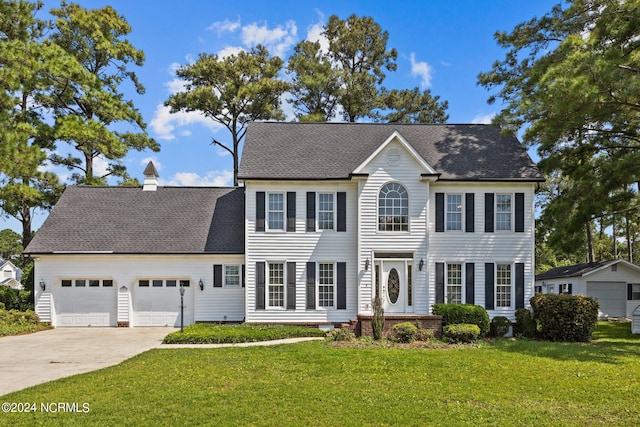 colonial home featuring a garage, driveway, roof with shingles, a front lawn, and a chimney