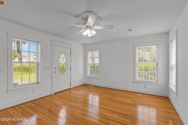 foyer entrance featuring light hardwood / wood-style floors, ceiling fan, and a textured ceiling