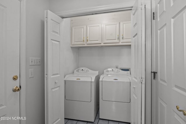 washroom with washing machine and dryer, light tile patterned floors, and cabinets