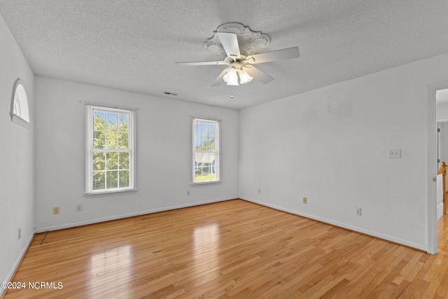 empty room with visible vents, baseboards, a ceiling fan, a textured ceiling, and light wood-style floors