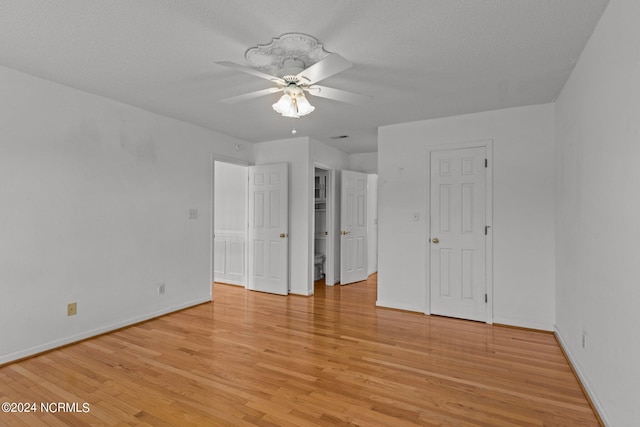 unfurnished bedroom featuring light wood-style floors, ceiling fan, baseboards, and a textured ceiling