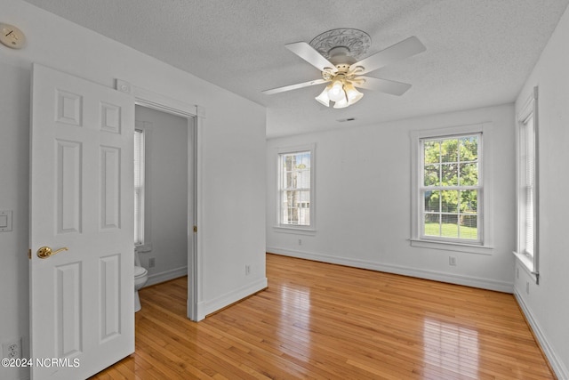 spare room featuring ceiling fan, light hardwood / wood-style flooring, and a textured ceiling