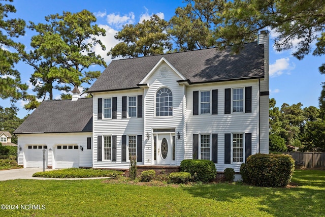 colonial home with a garage and a front lawn