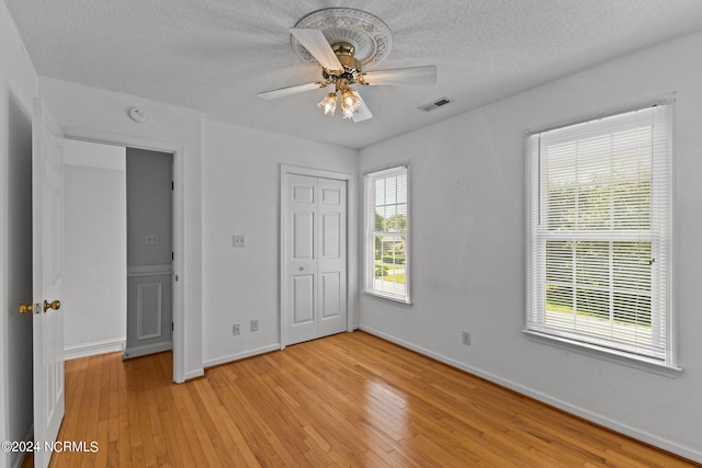 unfurnished bedroom with ceiling fan, light wood-type flooring, and a textured ceiling