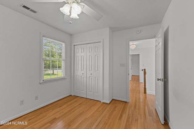 unfurnished bedroom featuring light wood finished floors, a closet, visible vents, ceiling fan, and baseboards