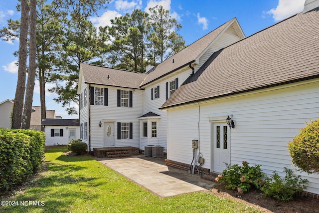 back of property featuring cooling unit and a yard