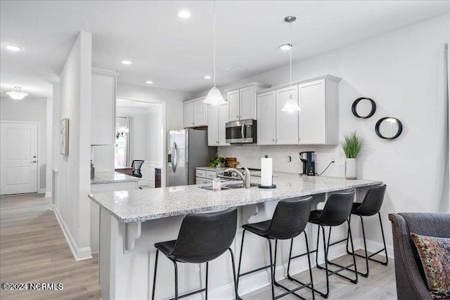 kitchen featuring stainless steel appliances, light hardwood / wood-style flooring, white cabinetry, sink, and kitchen peninsula