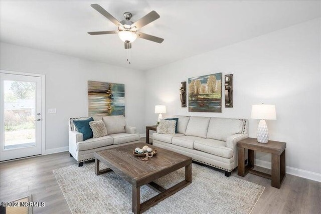 living room featuring ceiling fan, light wood-style flooring, and baseboards