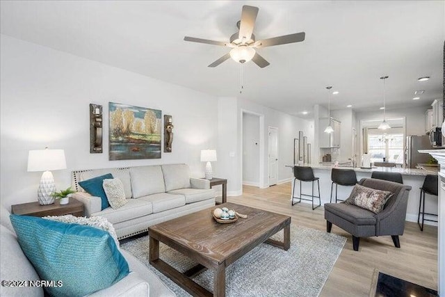 living room with light wood-style floors, baseboards, a ceiling fan, and recessed lighting