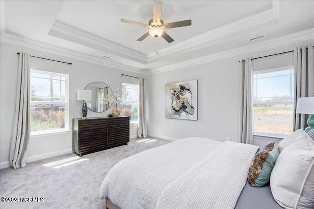 bedroom with a raised ceiling, light colored carpet, crown molding, and baseboards