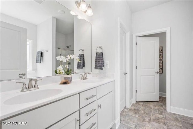 full bathroom with double vanity, a sink, and baseboards