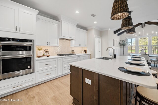 9307 Old Salem Way, Calabash, NC 28467 - kitchen with a sink, stainless steel appliances, a kitchen breakfast bar, white cabinetry, and backsplash