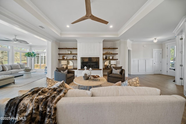 9307 Old Salem Way, Calabash, NC 28467 - living room with a ceiling fan, a tray ceiling, wood finished floors, a fireplace, and wainscoting
