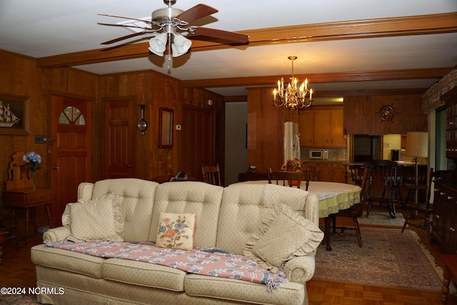 living room with crown molding, wood walls, dark parquet floors, and ceiling fan with notable chandelier