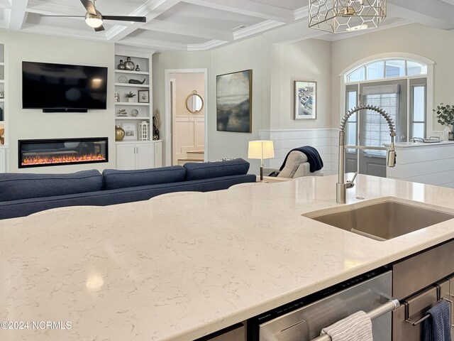 kitchen with sink, coffered ceiling, ceiling fan, ornamental molding, and stainless steel dishwasher