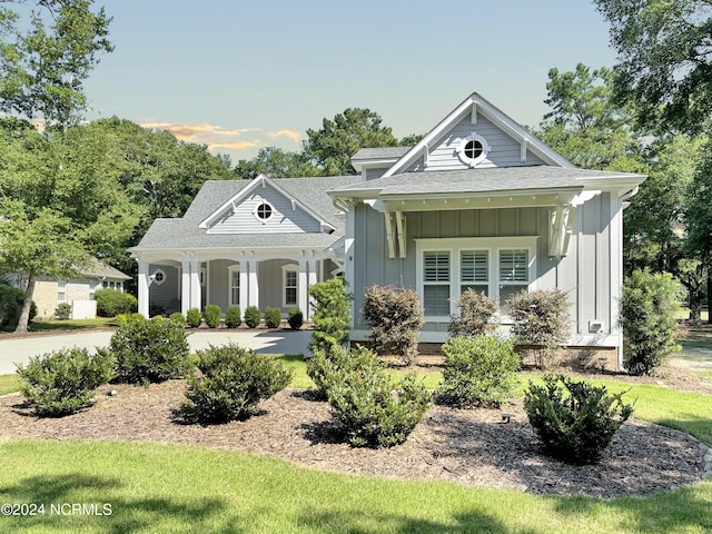 view of front of property featuring covered porch, roof with shingles, and board and batten siding